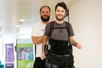 Foto: Maximilian Pölzl trainiert mit dem Exoskelett, unterstützt von Physiotherapeut Dennis Veit, regelmäßig seine Muskulatur.